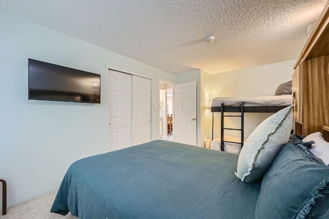 bedroom featuring light colored carpet, a textured ceiling, and a closet