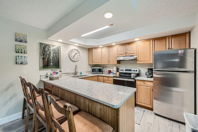 kitchen with a kitchen breakfast bar, sink, kitchen peninsula, and stainless steel appliances