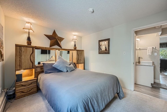 carpeted bedroom with sink and a textured ceiling