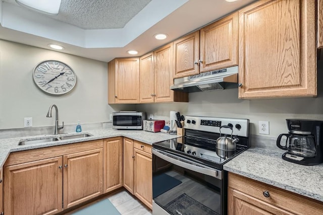 kitchen with sink, light stone counters, appliances with stainless steel finishes, and a textured ceiling