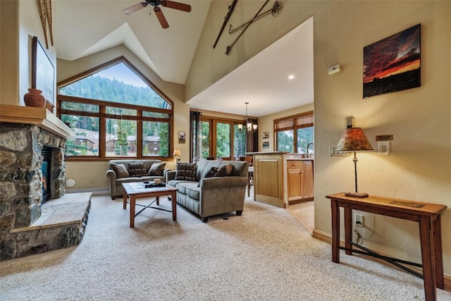 carpeted living room featuring a fireplace, ceiling fan with notable chandelier, high vaulted ceiling, and a wealth of natural light