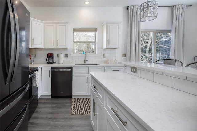 kitchen with white cabinetry, sink, decorative backsplash, hanging light fixtures, and black appliances