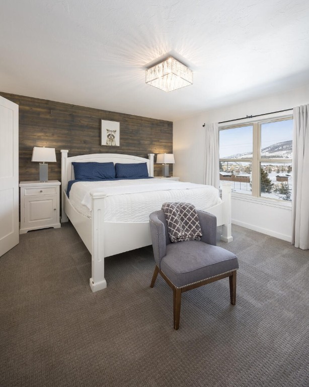 bedroom featuring dark colored carpet and wooden walls