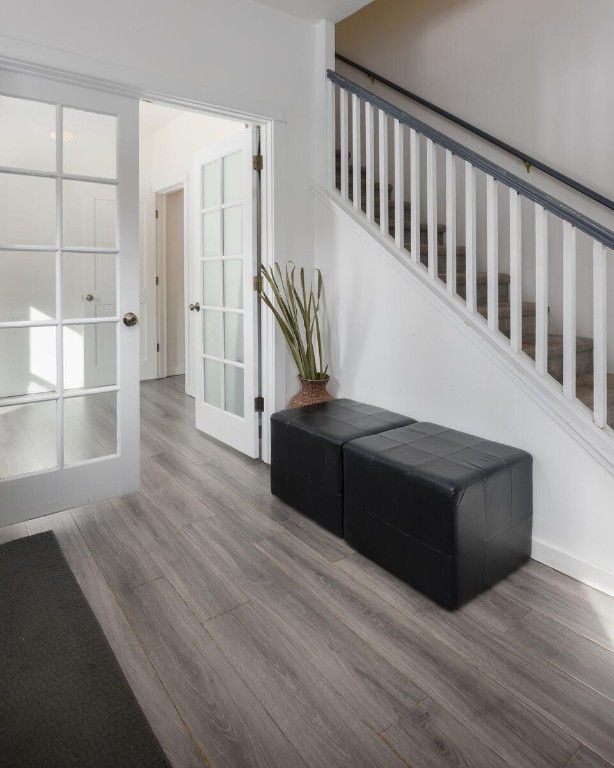 stairs with hardwood / wood-style flooring and french doors