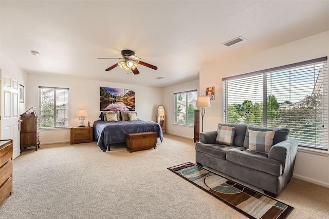 bedroom featuring ceiling fan, light colored carpet, and multiple windows