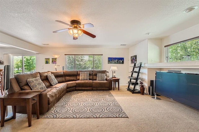 carpeted living room featuring ceiling fan, a healthy amount of sunlight, and a textured ceiling