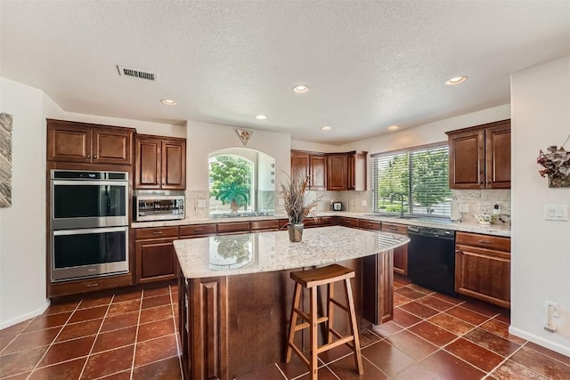 kitchen with dishwasher, a kitchen island, stainless steel double oven, and plenty of natural light