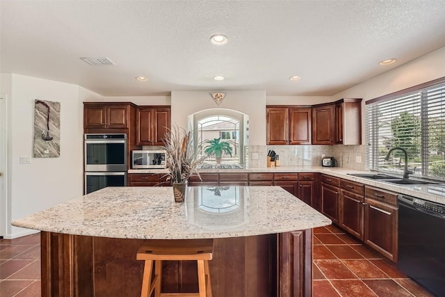 kitchen featuring sink, a kitchen island, plenty of natural light, and appliances with stainless steel finishes