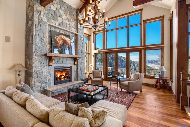 living room featuring hardwood / wood-style flooring, high vaulted ceiling, a chandelier, and a fireplace