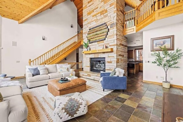 living room featuring high vaulted ceiling, stairway, a fireplace, and baseboards