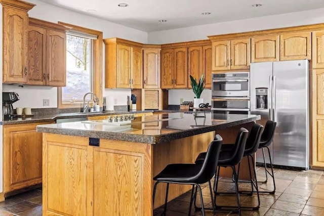 kitchen featuring a breakfast bar area, a kitchen island with sink, recessed lighting, a sink, and appliances with stainless steel finishes