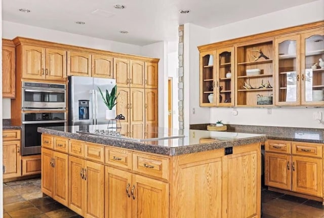 kitchen featuring stainless steel appliances, dark countertops, glass insert cabinets, and a kitchen island