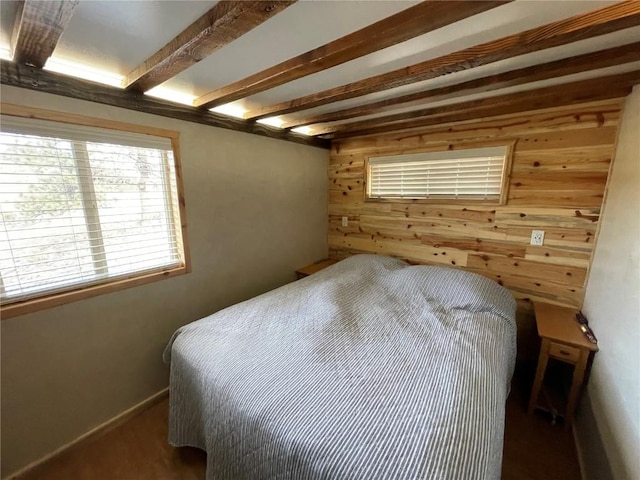 bedroom with beam ceiling and wooden walls