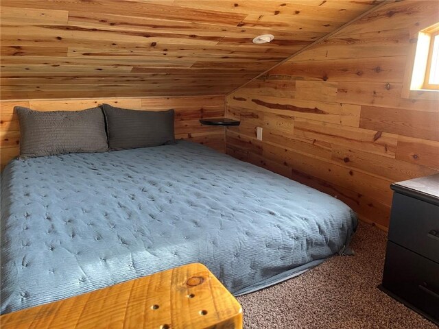 unfurnished bedroom featuring carpet, wooden ceiling, wooden walls, and vaulted ceiling