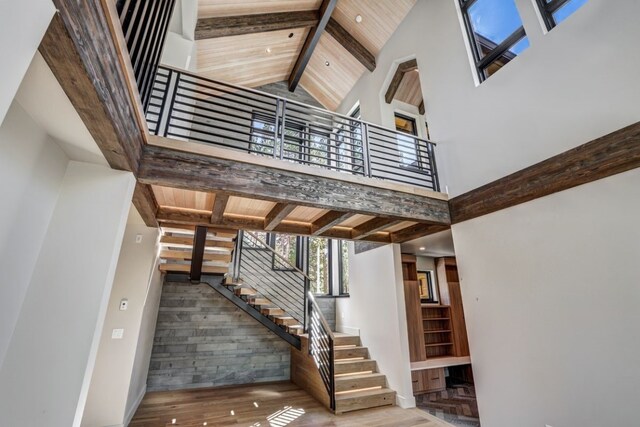 staircase with beamed ceiling, wood ceiling, a high ceiling, and hardwood / wood-style flooring