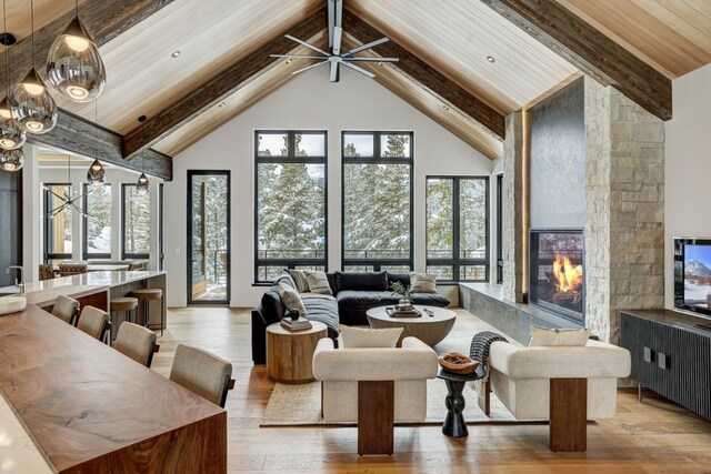 living room with light wood-type flooring, wood ceiling, ceiling fan, a tile fireplace, and plenty of natural light