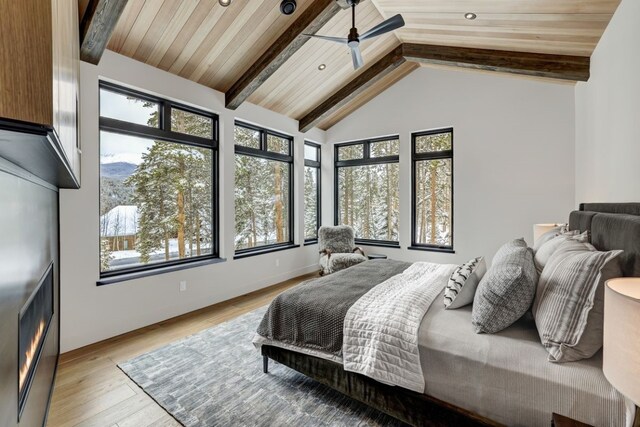 bedroom featuring vaulted ceiling with beams, light wood-type flooring, ceiling fan, and wooden ceiling