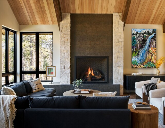 living room featuring a healthy amount of sunlight, a stone fireplace, lofted ceiling, and wood ceiling