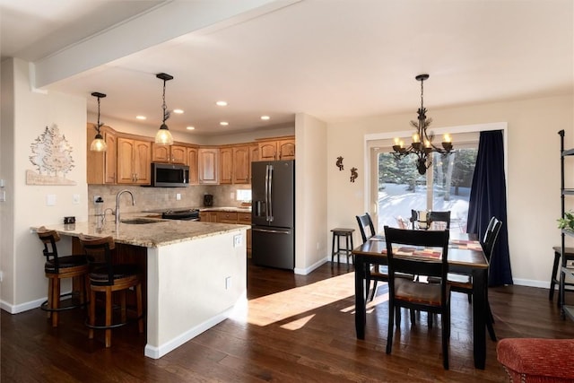 kitchen featuring tasteful backsplash, sink, kitchen peninsula, stainless steel appliances, and light stone countertops