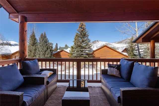 snow covered deck featuring an outdoor living space and a mountain view