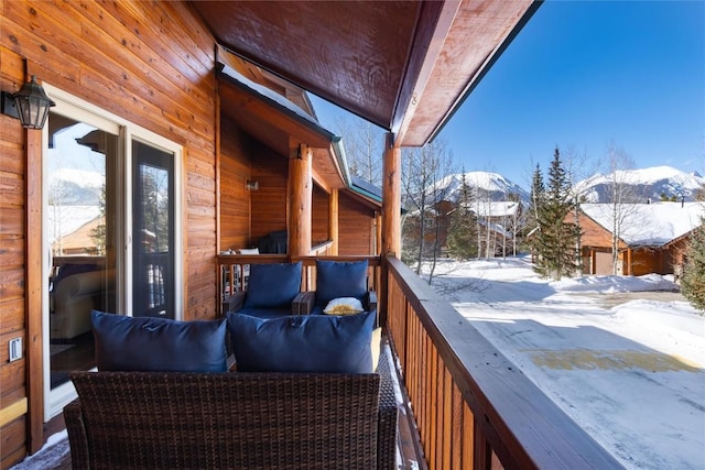 snow covered back of property featuring a mountain view