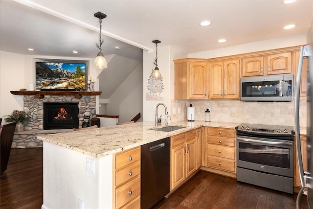 kitchen featuring appliances with stainless steel finishes, pendant lighting, sink, kitchen peninsula, and light stone countertops