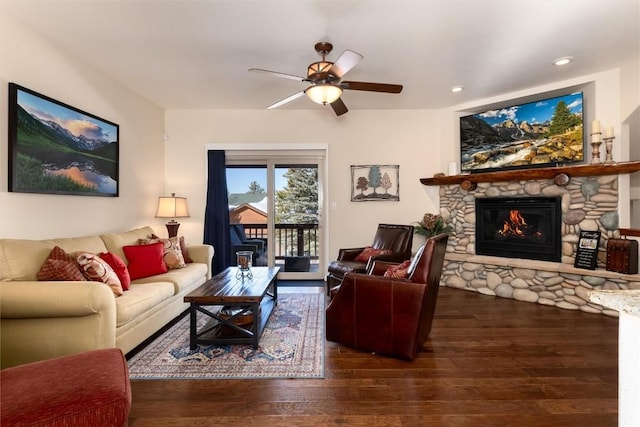 living room featuring ceiling fan, a stone fireplace, and dark hardwood / wood-style flooring