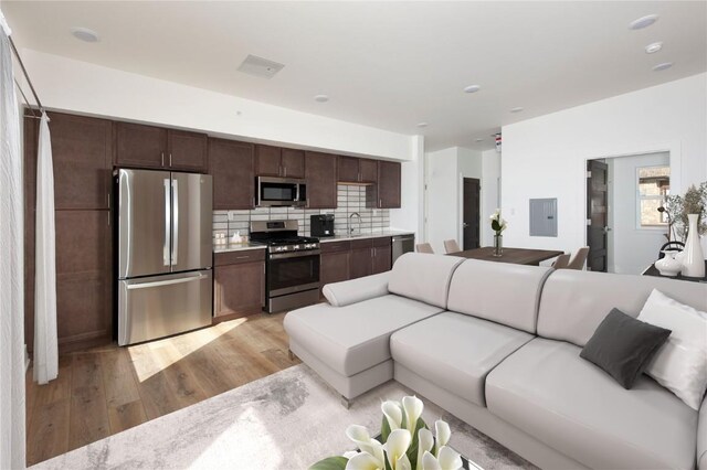 living room with electric panel, light hardwood / wood-style flooring, and sink