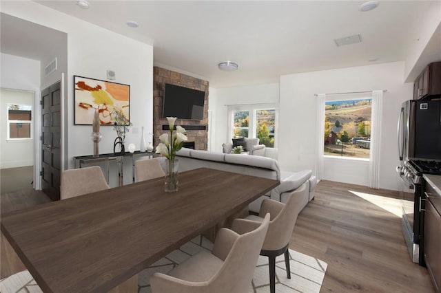 dining space featuring light hardwood / wood-style flooring and a stone fireplace