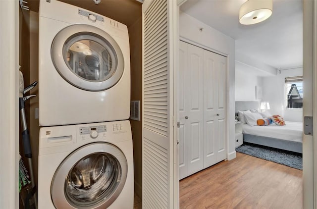 washroom featuring laundry area, stacked washing maching and dryer, and wood finished floors