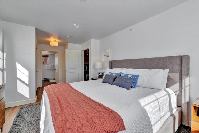 bedroom featuring baseboards, baseboard heating, and wood finished floors