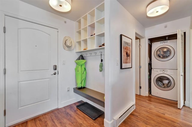 mudroom with a baseboard radiator, stacked washer and clothes dryer, light wood-style flooring, and baseboards