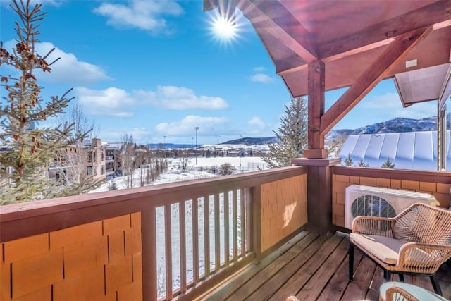 snow covered deck featuring ac unit and a mountain view