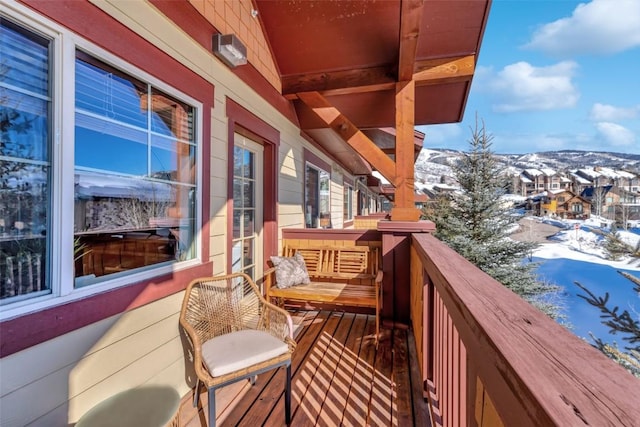 snow covered back of property featuring a residential view and a mountain view