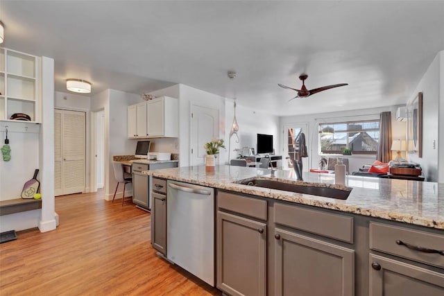 kitchen featuring light wood finished floors, open floor plan, light stone countertops, stainless steel dishwasher, and a sink