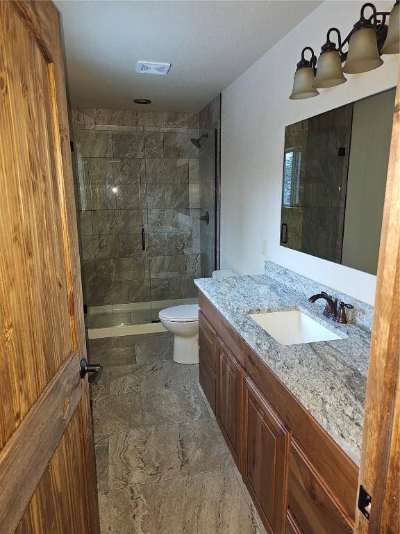 bathroom with vanity, toilet, and a tile shower