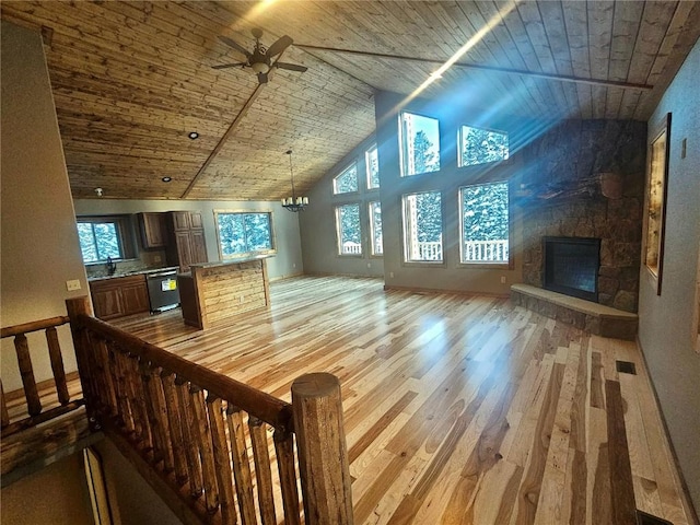 unfurnished living room with a stone fireplace, ceiling fan, wood ceiling, and vaulted ceiling