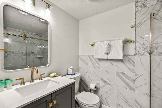 bathroom featuring vanity, toilet, a shower with door, and tile walls