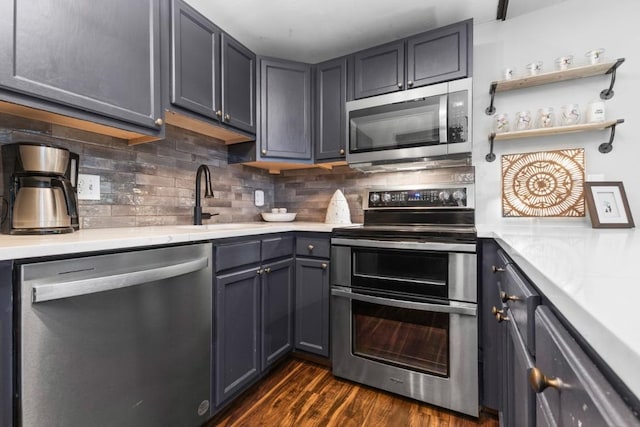 kitchen featuring tasteful backsplash, stainless steel appliances, light countertops, and a sink