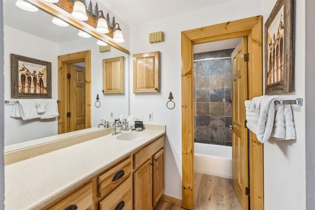 bathroom with vanity, wood-type flooring, and tiled shower / bath combo