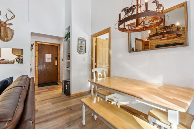 dining room with a chandelier, light hardwood / wood-style flooring, and built in features