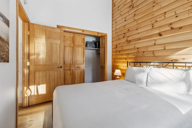 bedroom featuring log walls, light hardwood / wood-style flooring, and a closet