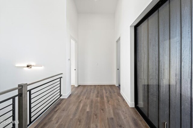 corridor featuring a towering ceiling and dark wood-type flooring