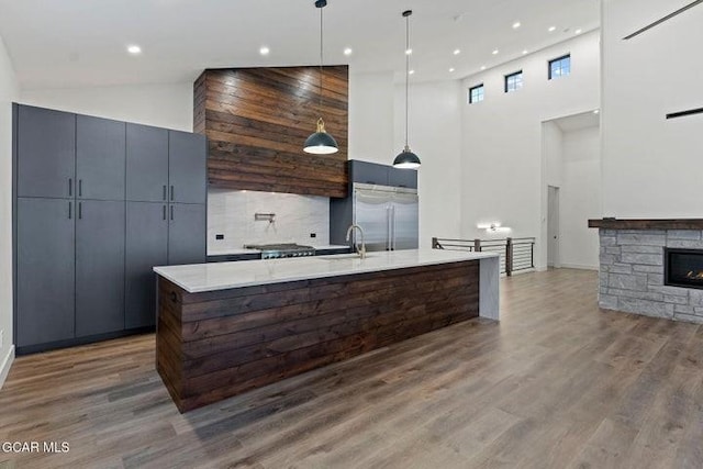 kitchen featuring backsplash, stainless steel built in fridge, a towering ceiling, and hanging light fixtures