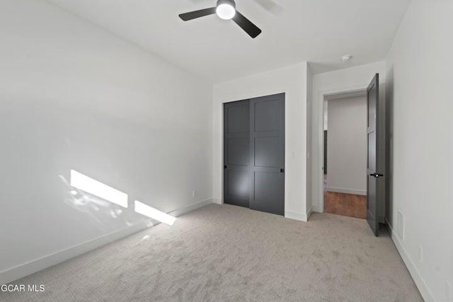 unfurnished bedroom with light colored carpet, a closet, and ceiling fan