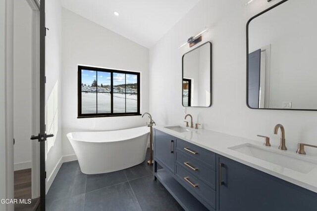 bathroom featuring a bathing tub, tile patterned flooring, vanity, and vaulted ceiling