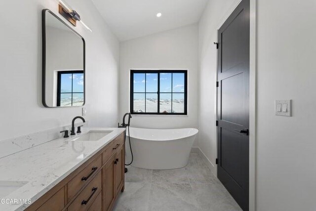 bathroom with a bathing tub, vanity, a wealth of natural light, and tile patterned flooring