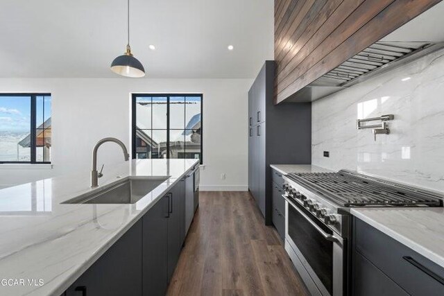 kitchen with high end range, light stone countertops, backsplash, sink, and decorative light fixtures