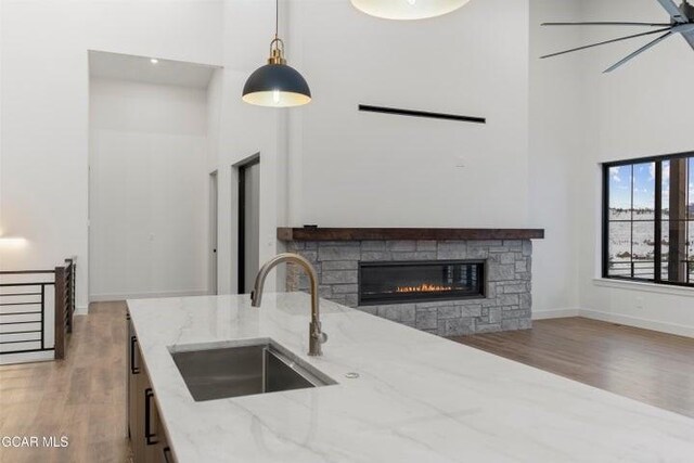 kitchen with light stone countertops, sink, decorative light fixtures, a high ceiling, and a stone fireplace