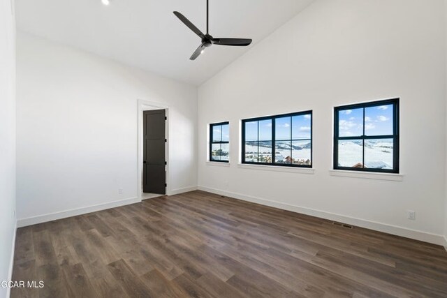 empty room with ceiling fan, dark hardwood / wood-style floors, and high vaulted ceiling